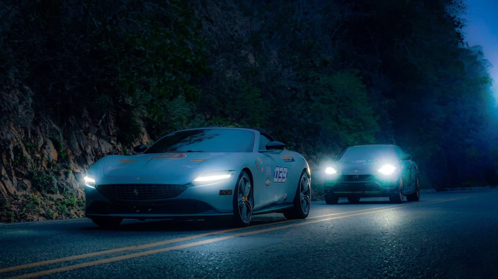 Sports cars on a coastal road relit for blue hour