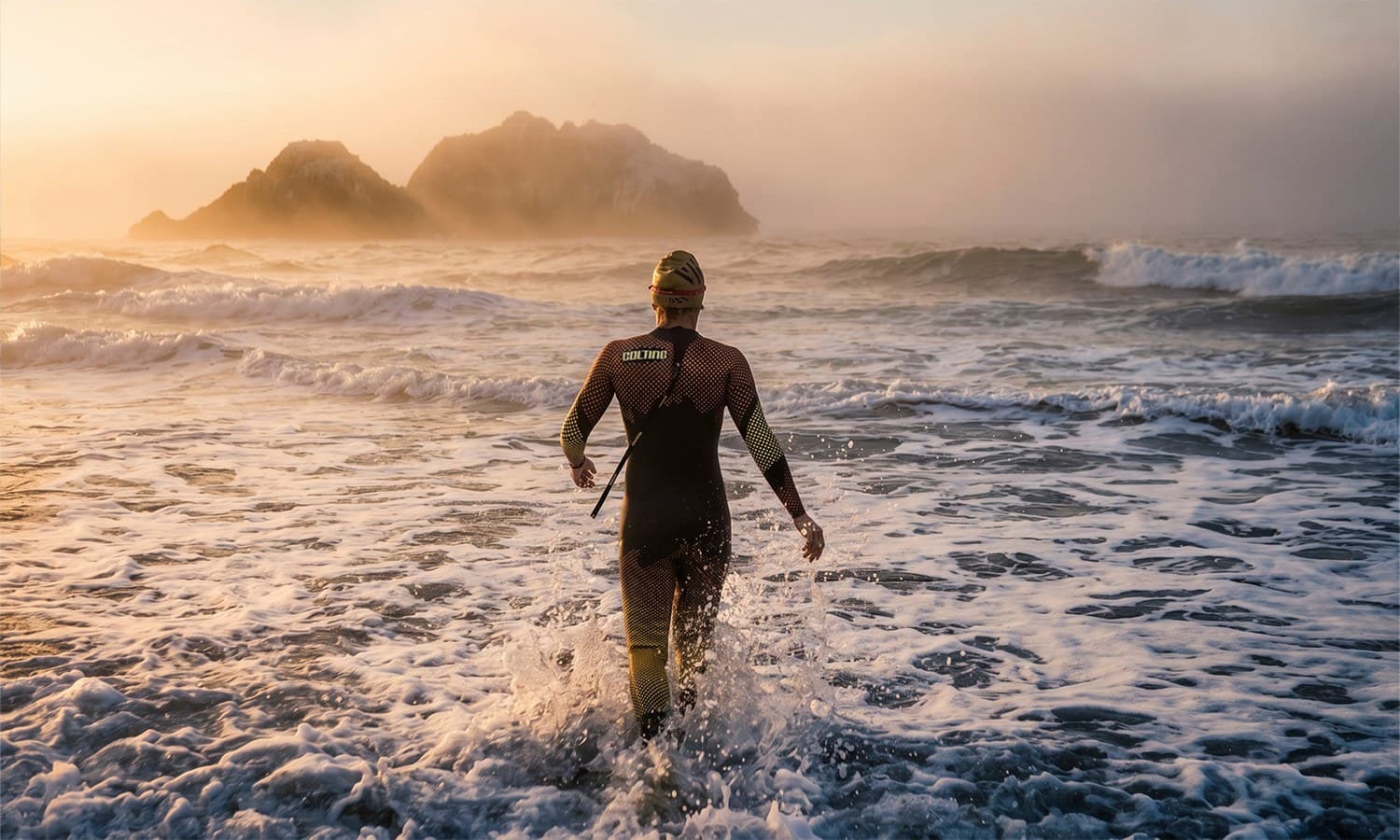 Swimmer heading into the sea relit with golden fog